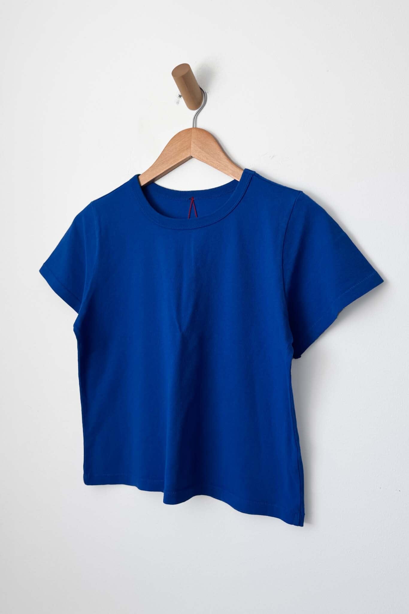 Cobalt blue t-shirt on a wooden hanger against a white background