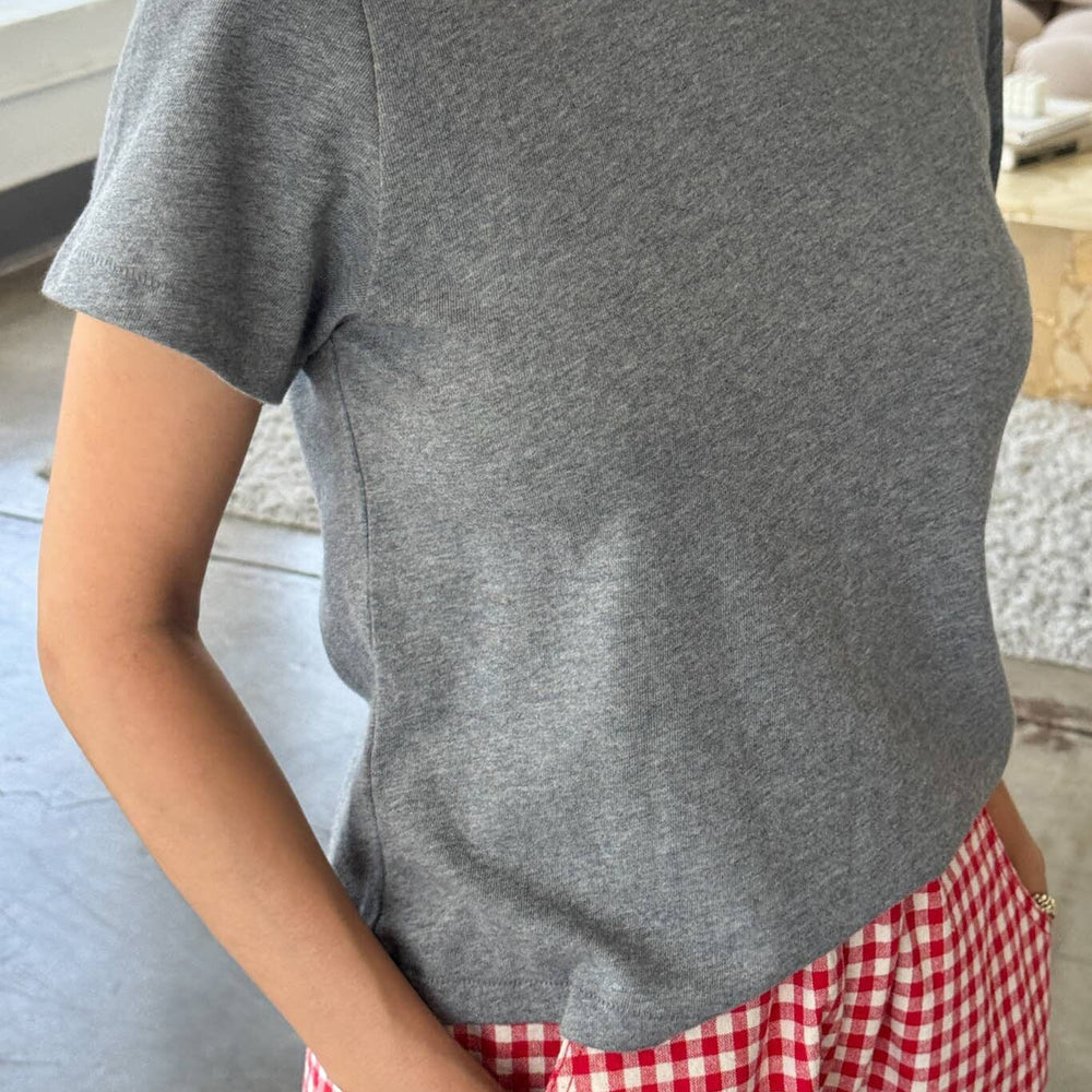 
                  
                    Person wearing a gray t-shirt and red checkered pants indoors.
                  
                