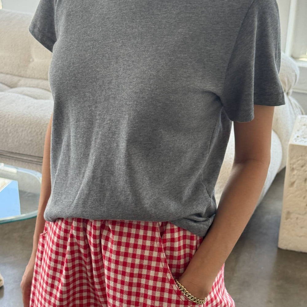 
                  
                    Person wearing a gray t-shirt and red checkered pants in a casual setting.
                  
                