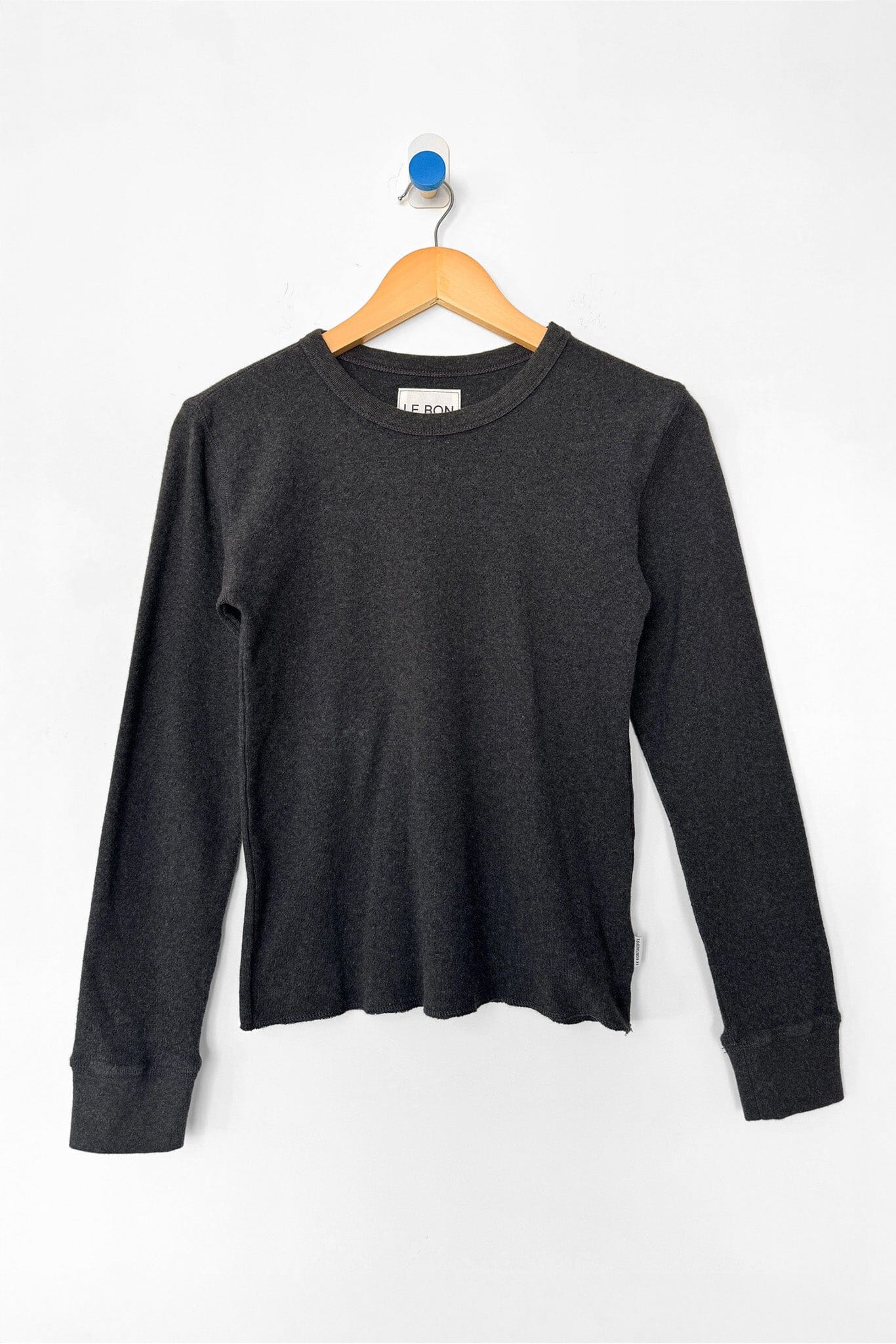 Black long-sleeve shirt on a wooden hanger against a white background