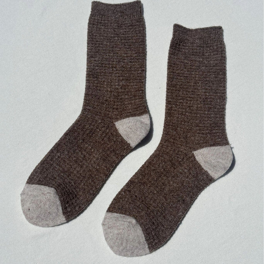 Pair of brown wool socks with gray toes and cuffs on a light gray background