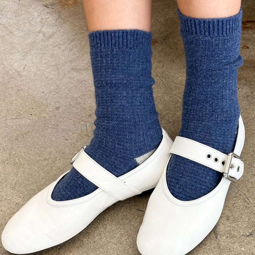 
                  
                    White shoes with blue socks on a neutral background
                  
                