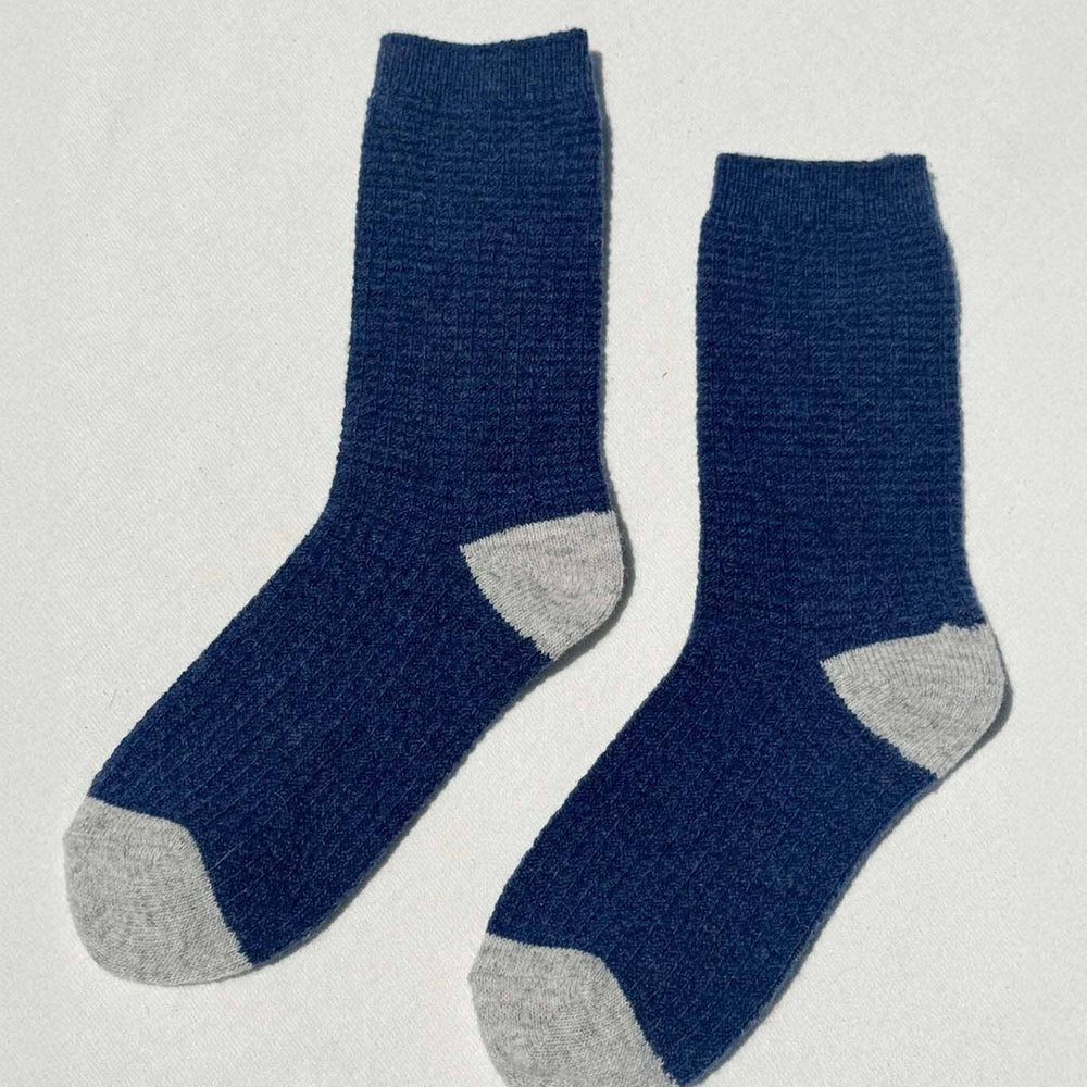 Pair of blue socks with gray toes and heels on a light gray background