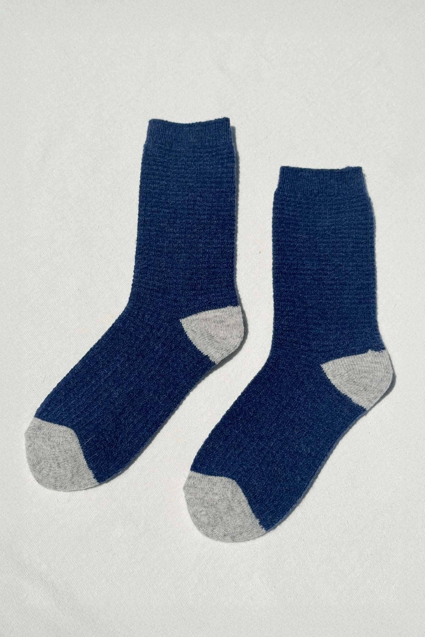 Pair of blue socks with gray toes and heels on a light gray background