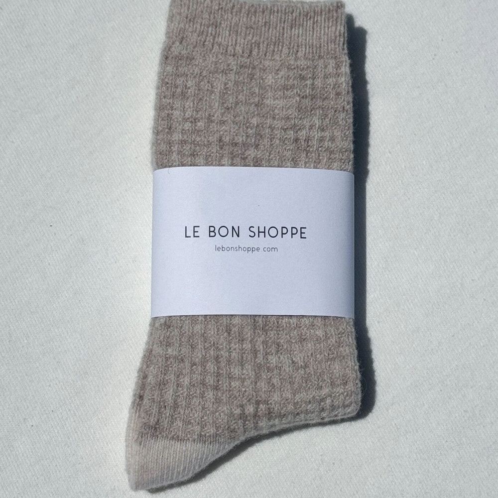 
                  
                    Pair of brown textured socks with a white label on a light gray background
                  
                