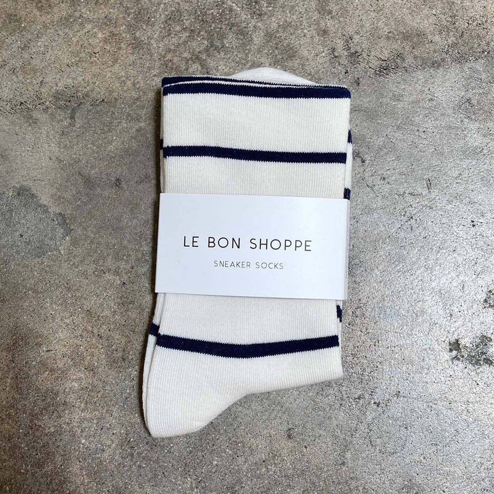 Pair of white socks with navy stripes on a gray surface, featuring 'Le Bon Shoppe' packaging.