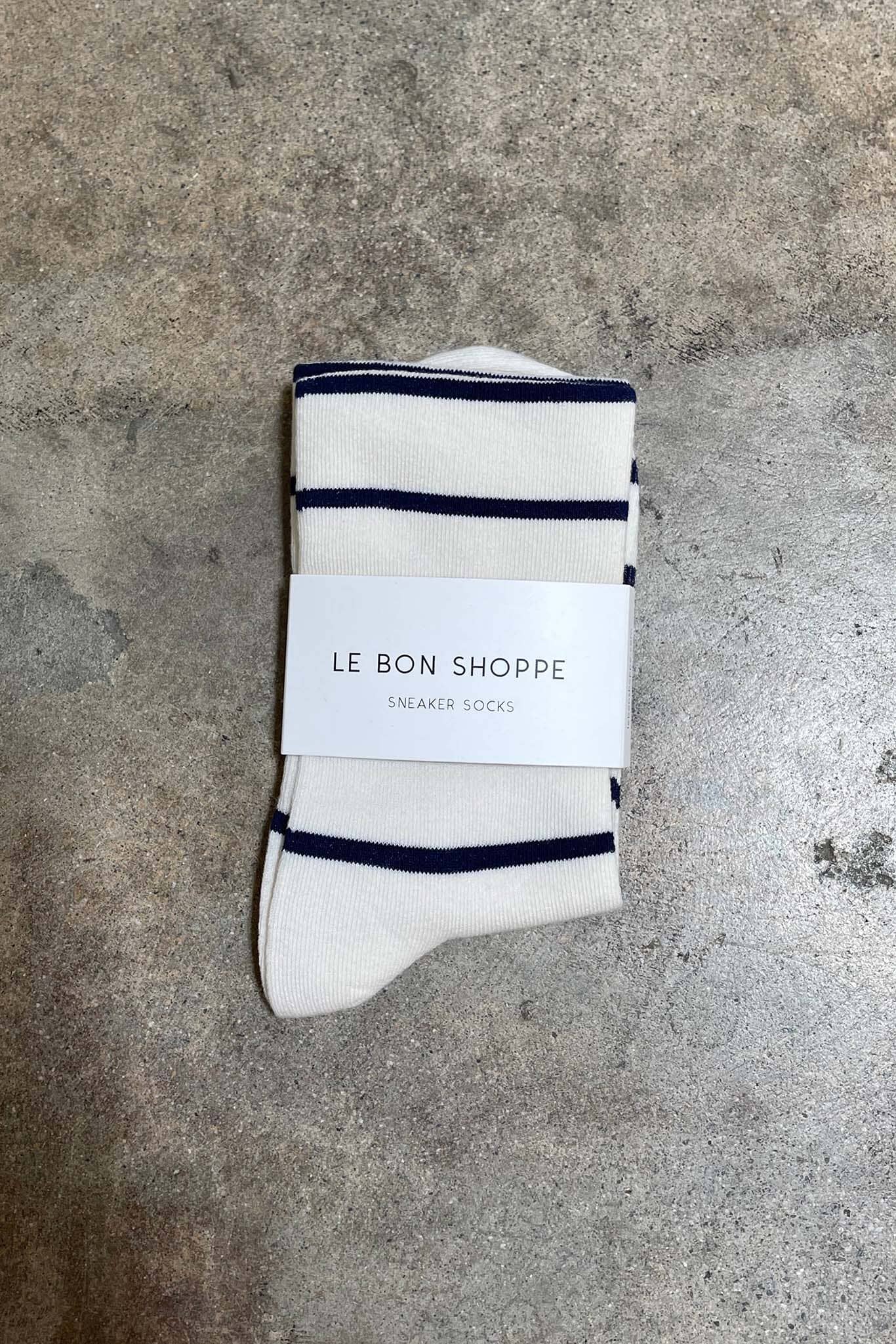 Pair of white socks with navy stripes on a gray surface, featuring 'Le Bon Shoppe' packaging.