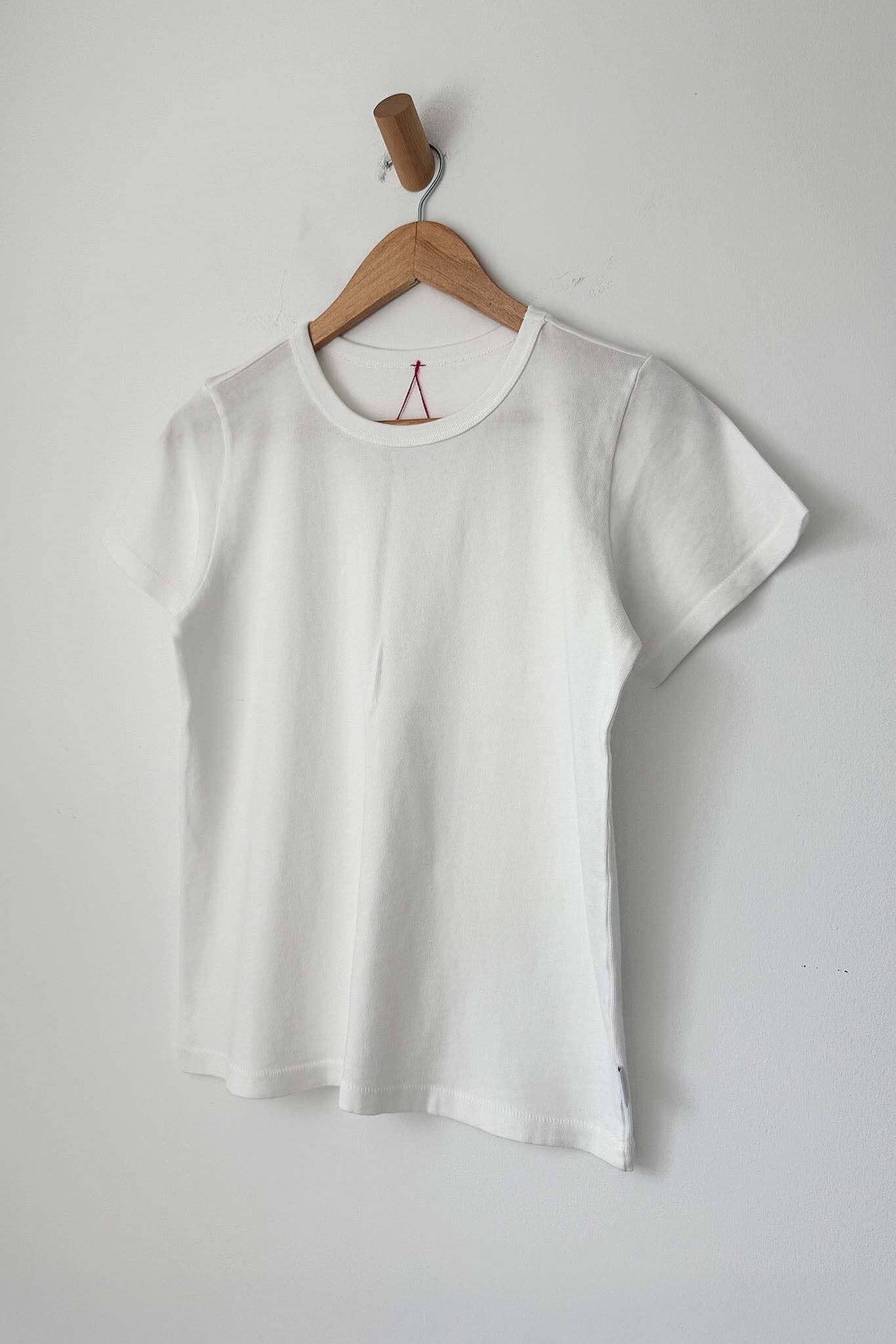 White t-shirt on a wooden hanger against a plain background