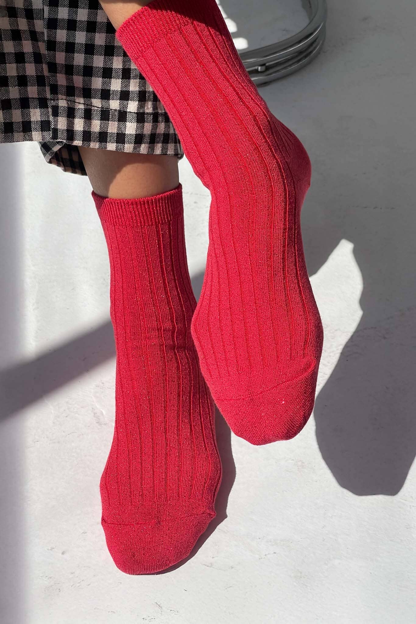 Red glitter socks worn with a checkered skirt on a light background