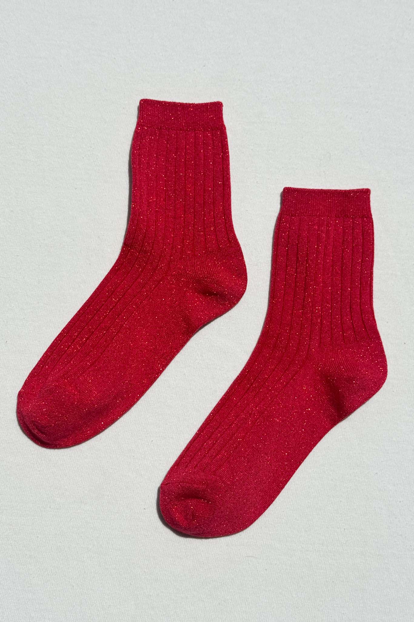 Pair of red glitter socks on a light gray background