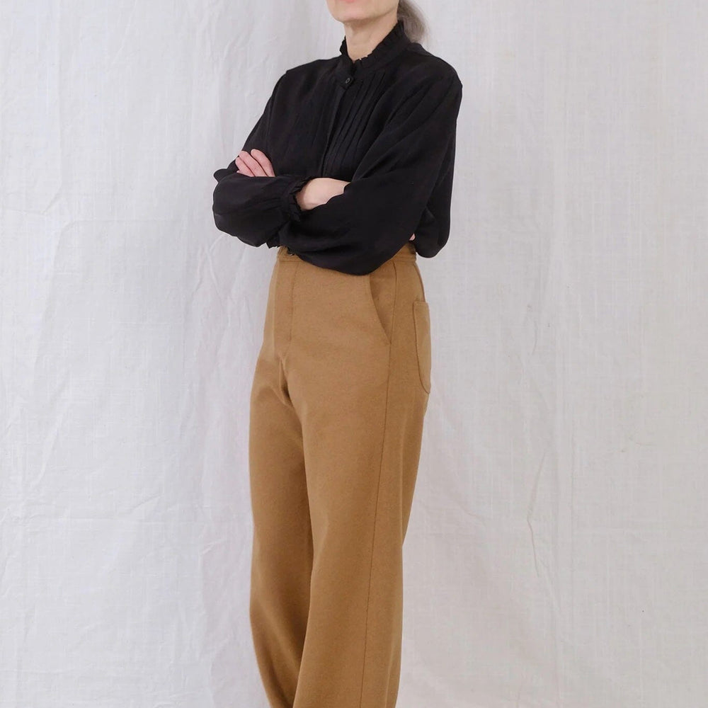 A woman wears the Uqnatu Sailor pants in camel wool. Available to purchase at M.Patmos in Brooklyn, New York.