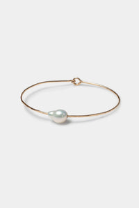 Gold bracelet with a white baroque pearl on a white background