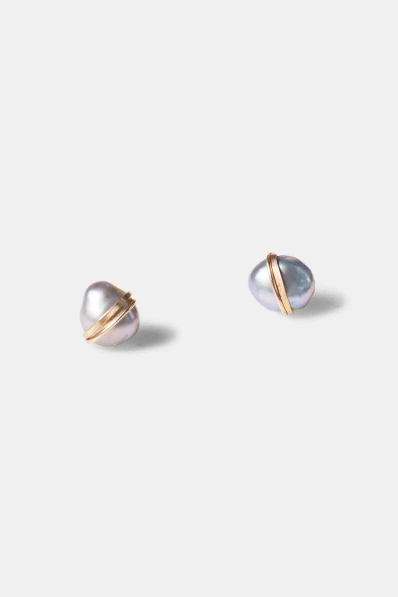 Pair of pearl earrings with gold accents on a light gray background