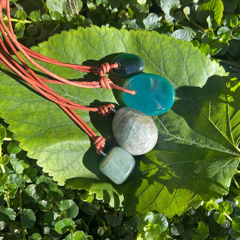 Cord necklaces with turquoise and green jade beads resting on a green leaf