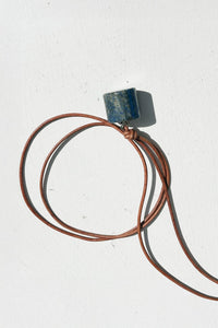 Lapis cylander necklace with a square pendant on a white background