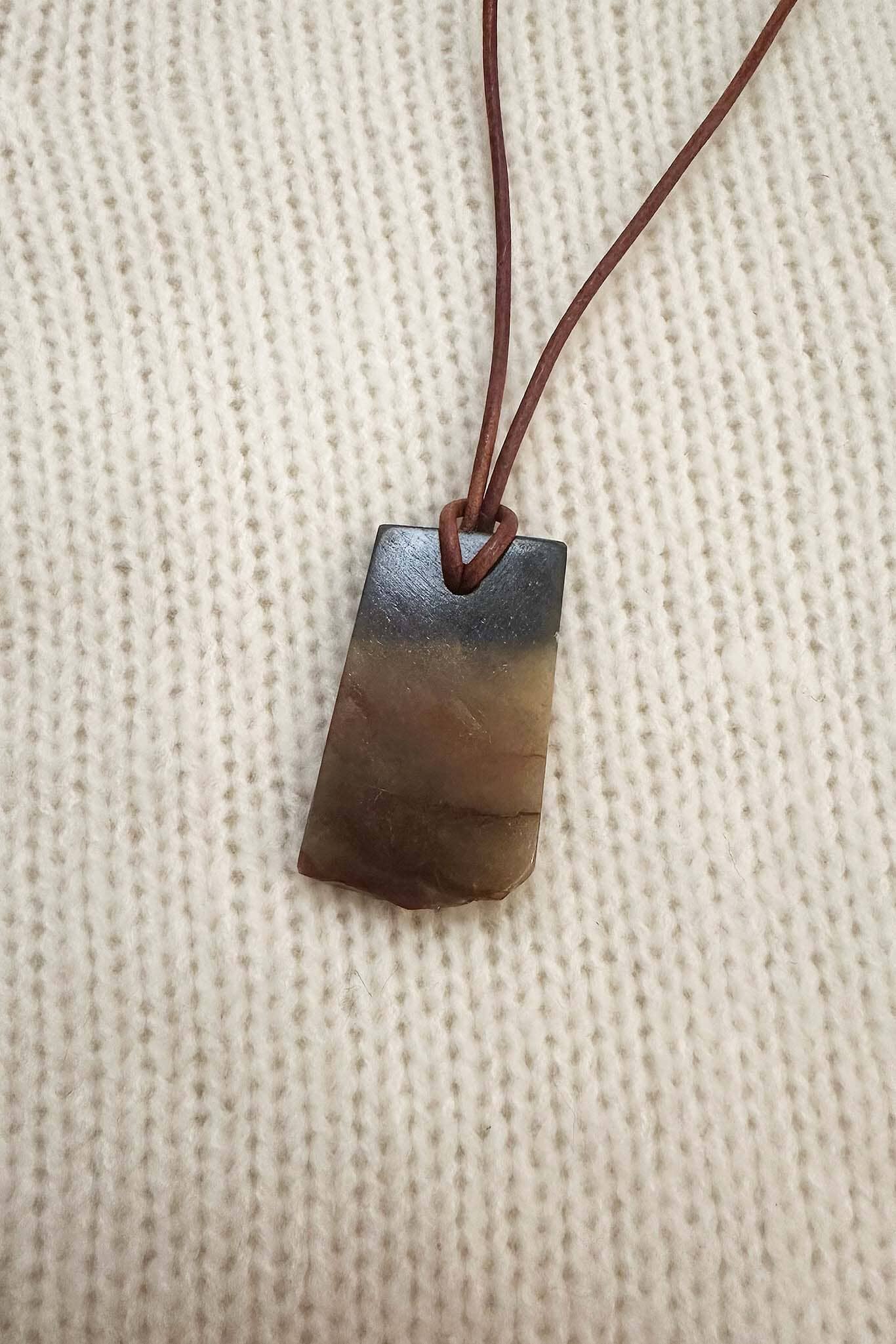 Rectangular tiger's eye pendent withma textured beige background