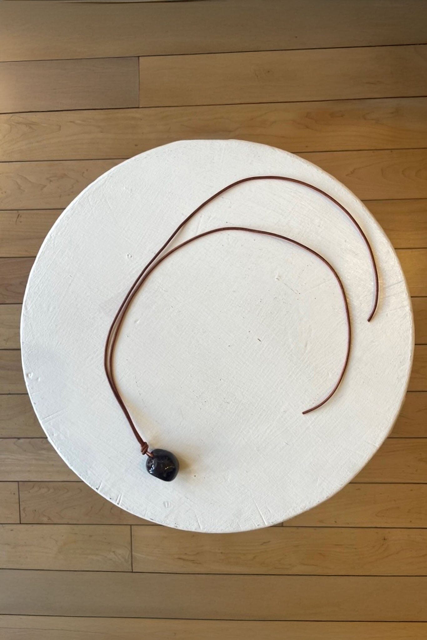 Rectangular natural garnet stone with a brown cord on a wooden floor