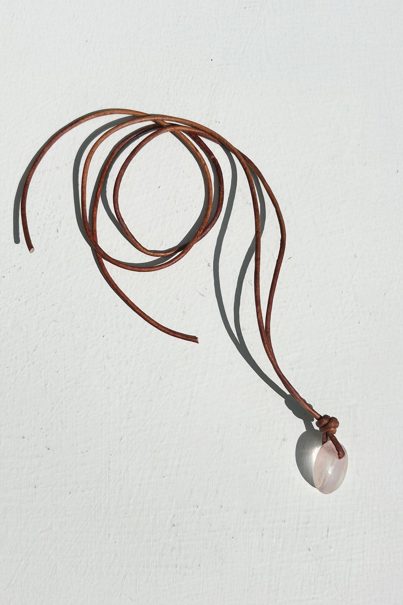 Necklace with a pink quartz pendant on a light gray background