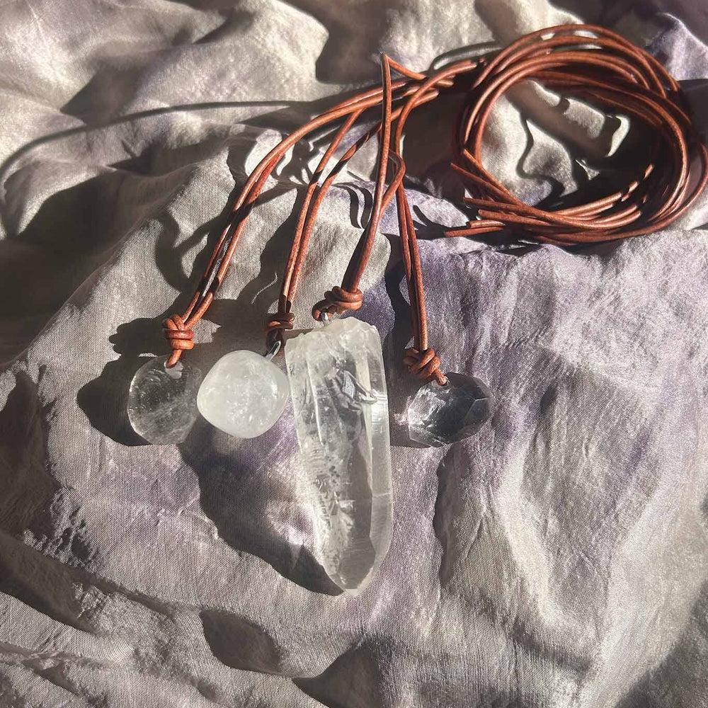 
                  
                    Crystal necklaces with natural brown cord on a textured fabric surface
                  
                