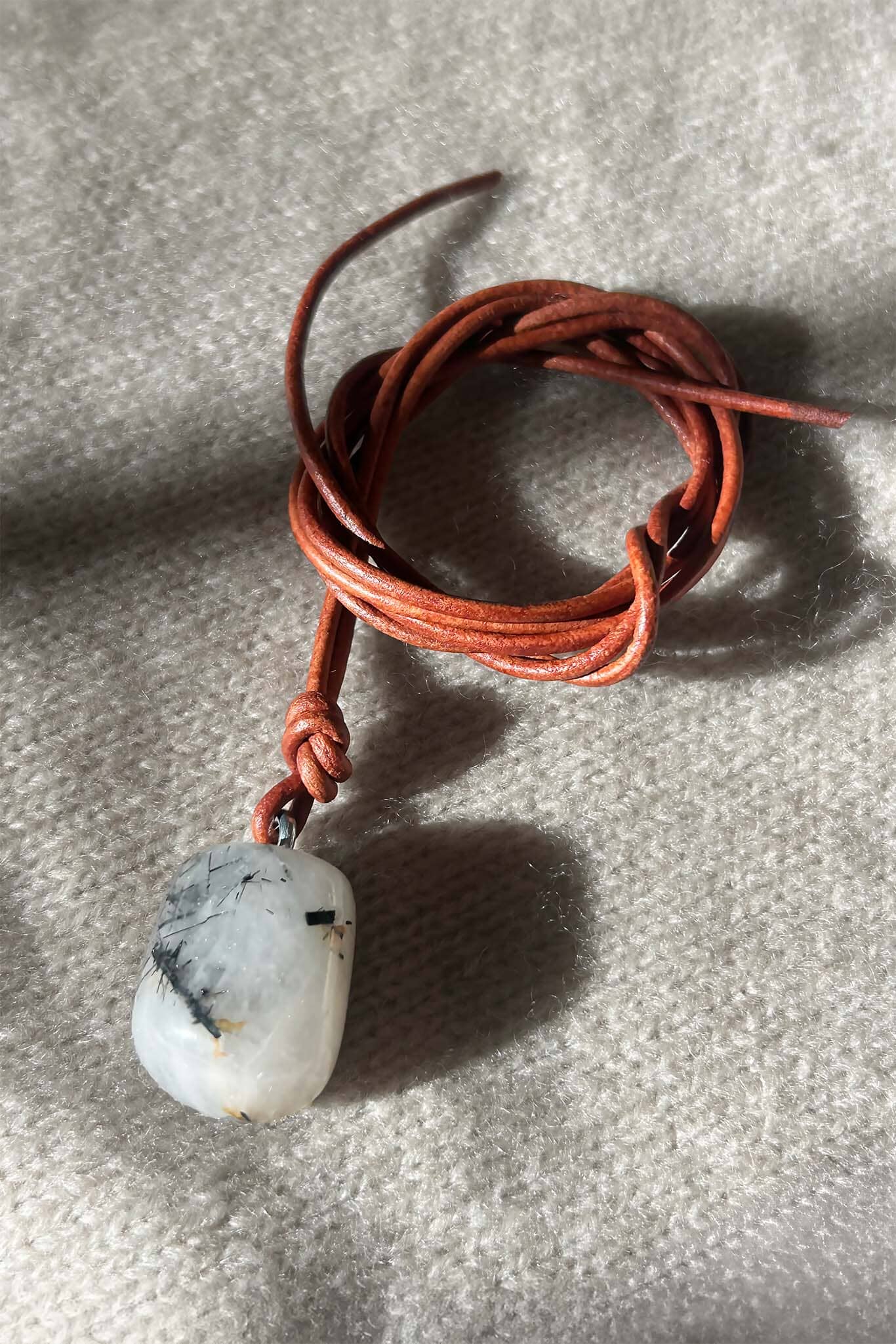 Necklace with a white and black stone pendant on a textured surface