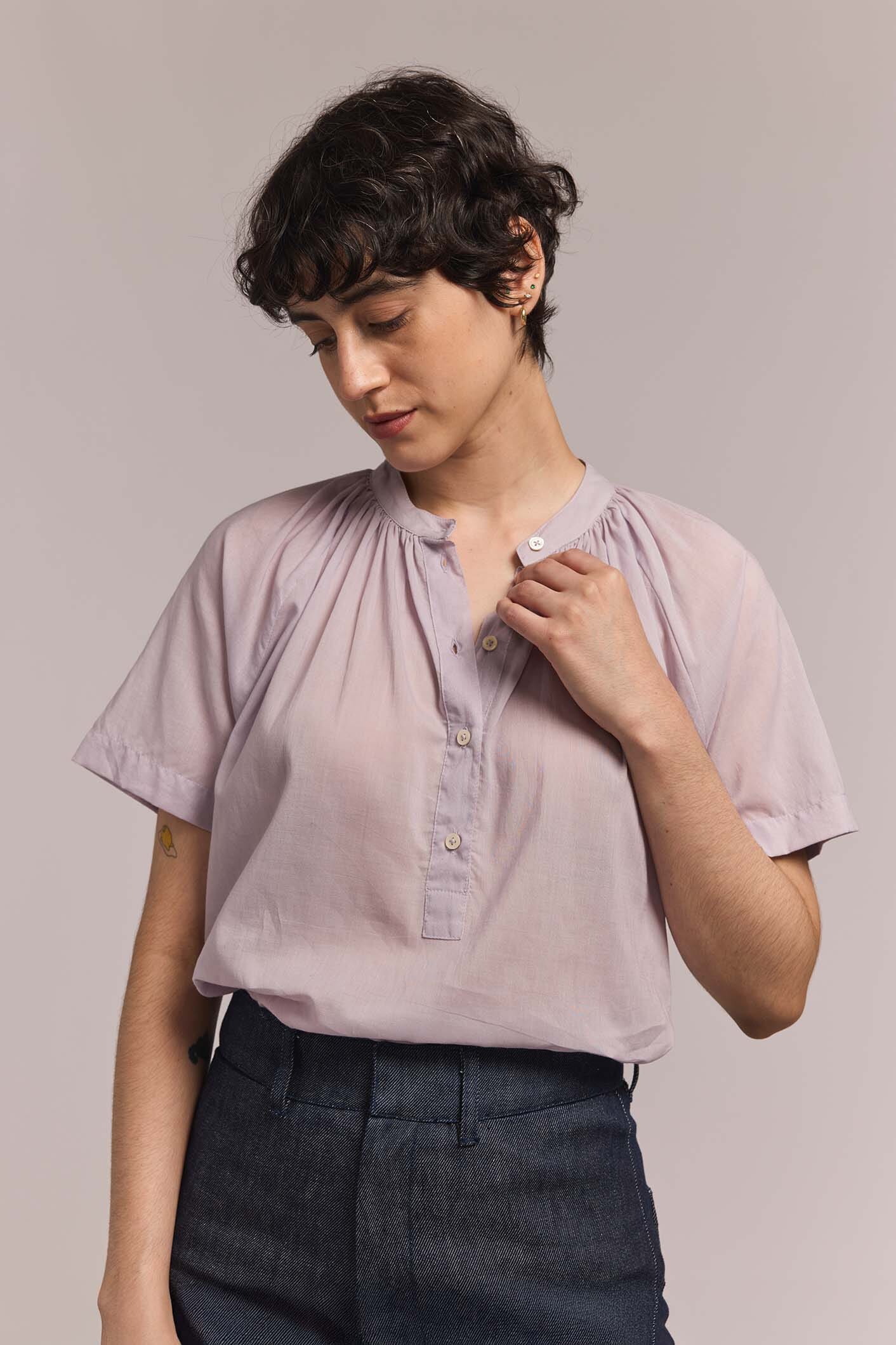 Woman wears a light purple blouse with a plain background