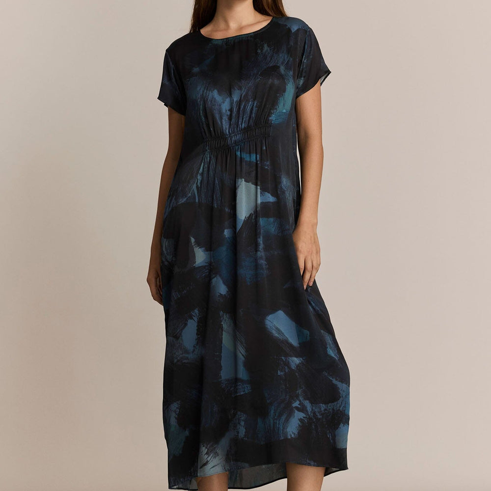 Woman wearing a dark blue patterned dress against a beige background