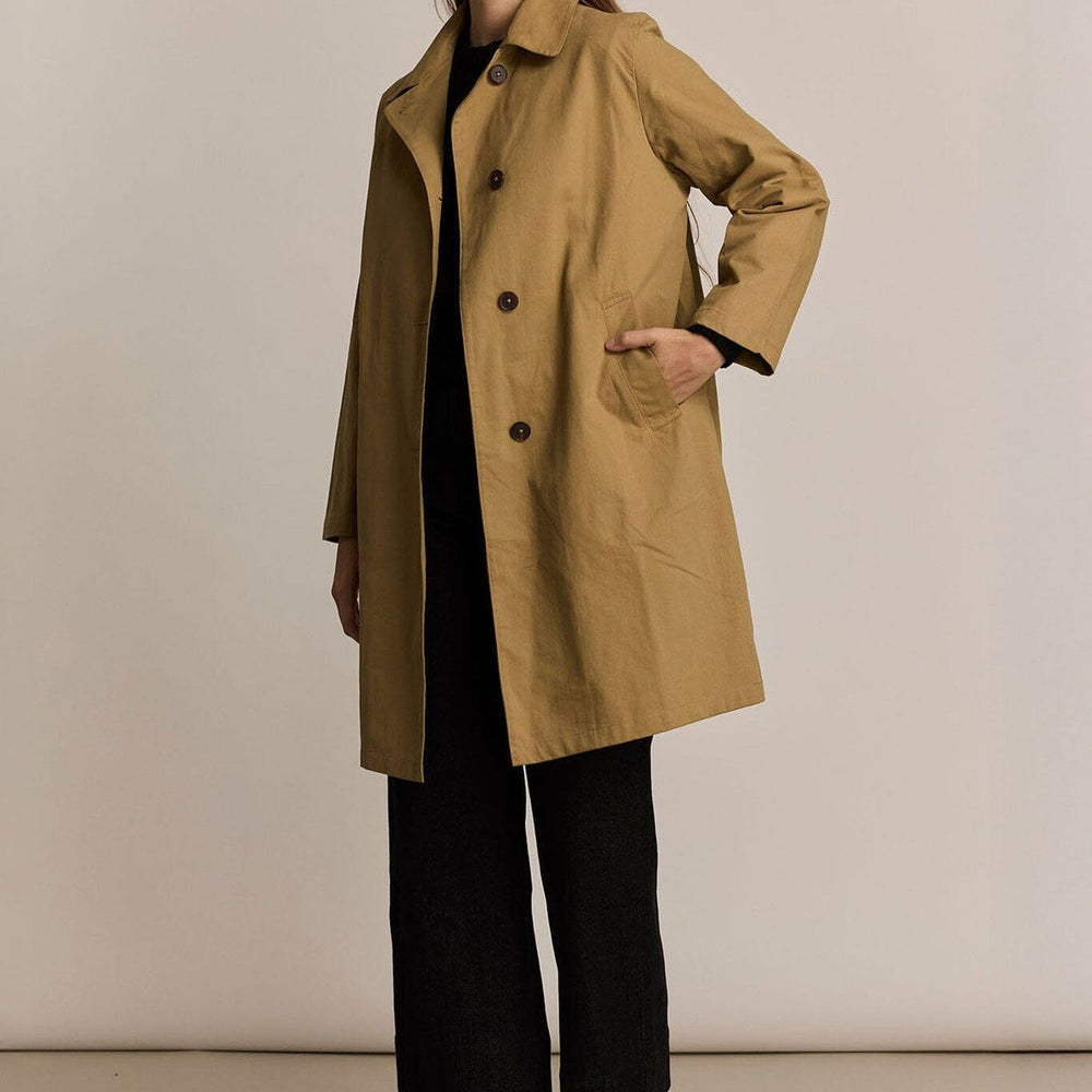 
                  
                    Woman wearing a beige trench coat with pockets against a plain background
                  
                