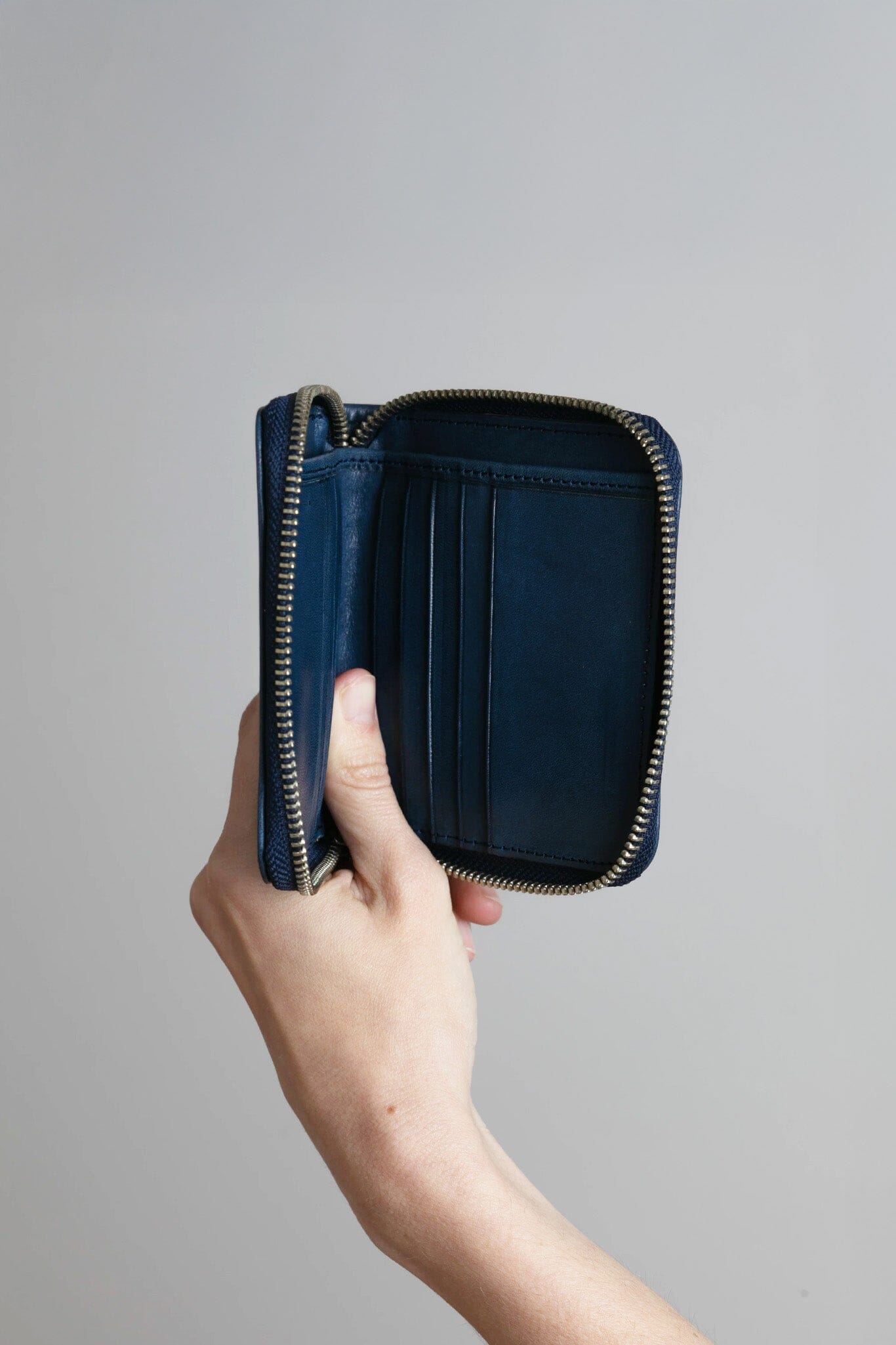 Hand holding a blue wallet against a gray background