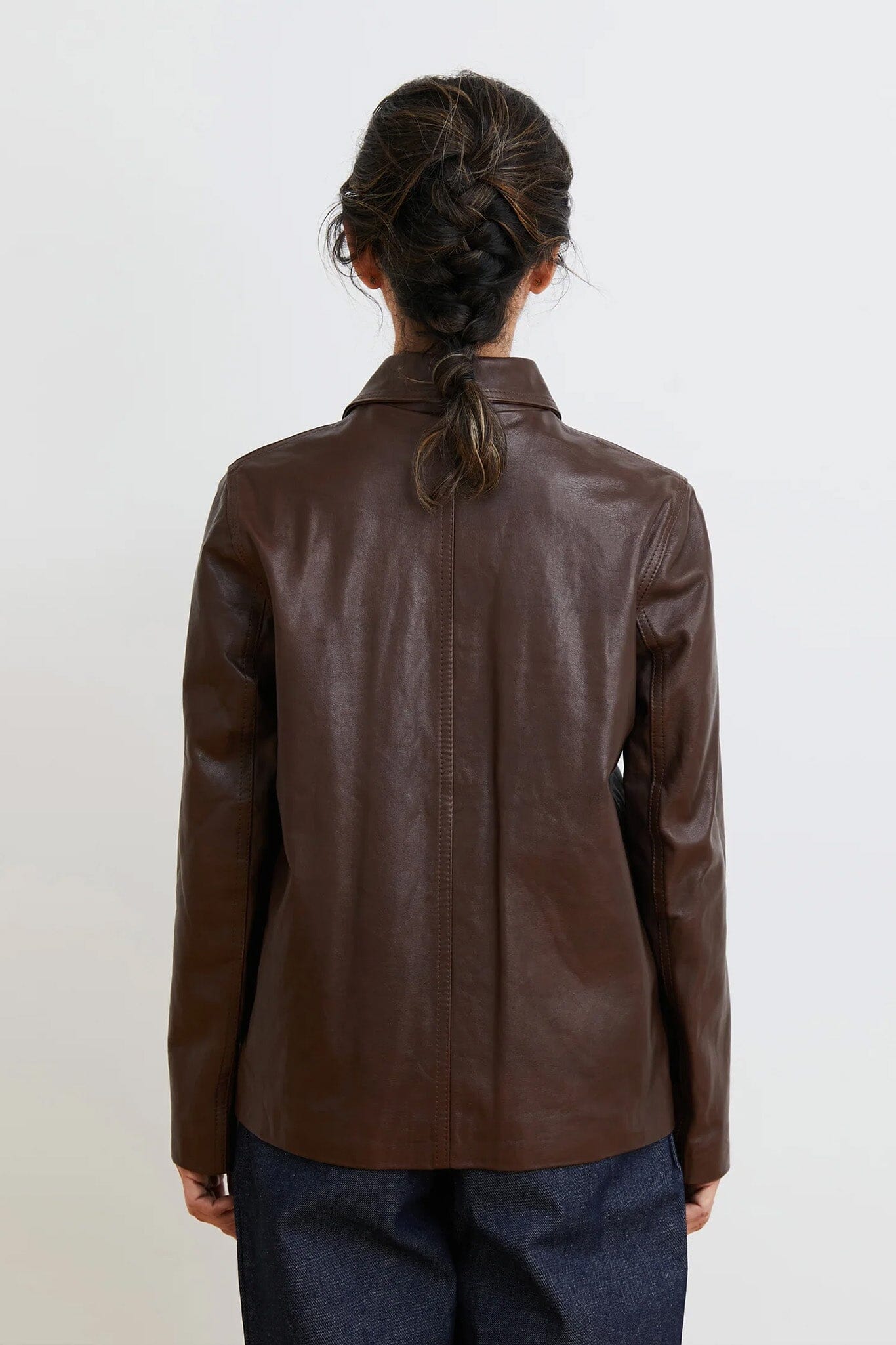 Brown leather jacket worn by a person on a white background