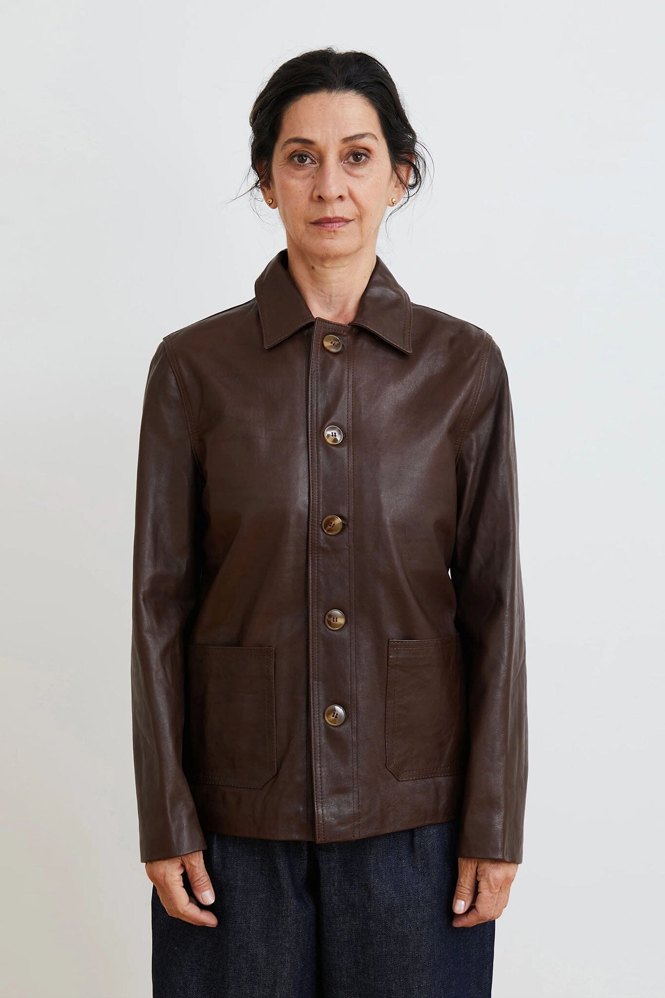 Woman wearing a brown leather jacket on a plain background