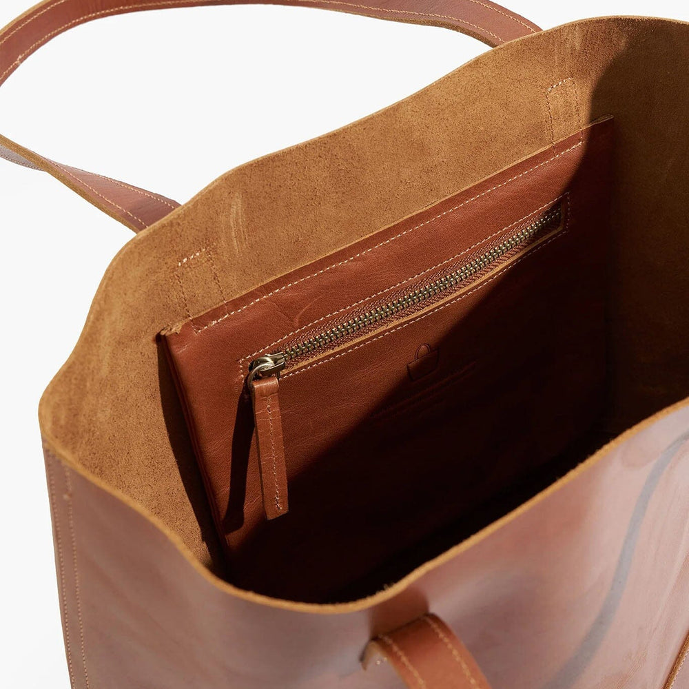 
                  
                    Brown leather tote bag with a zipper on a white background
                  
                