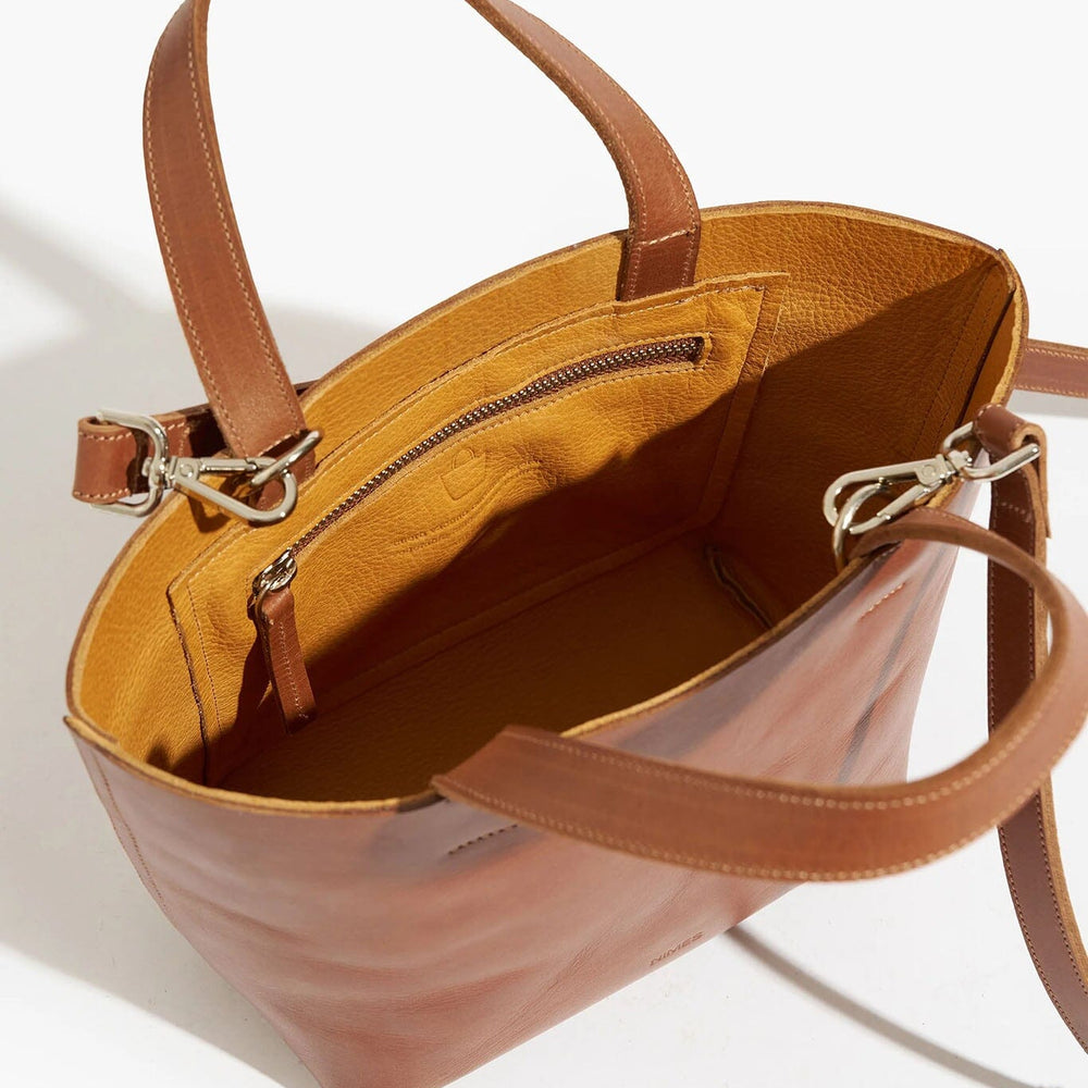 Brown leather handbag with open top on a white background