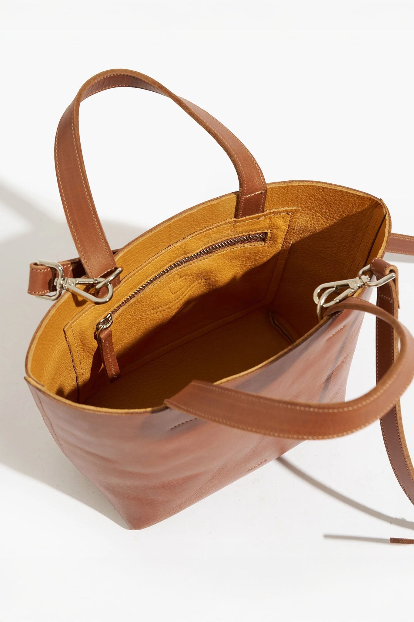 Brown leather handbag with open top on a white background