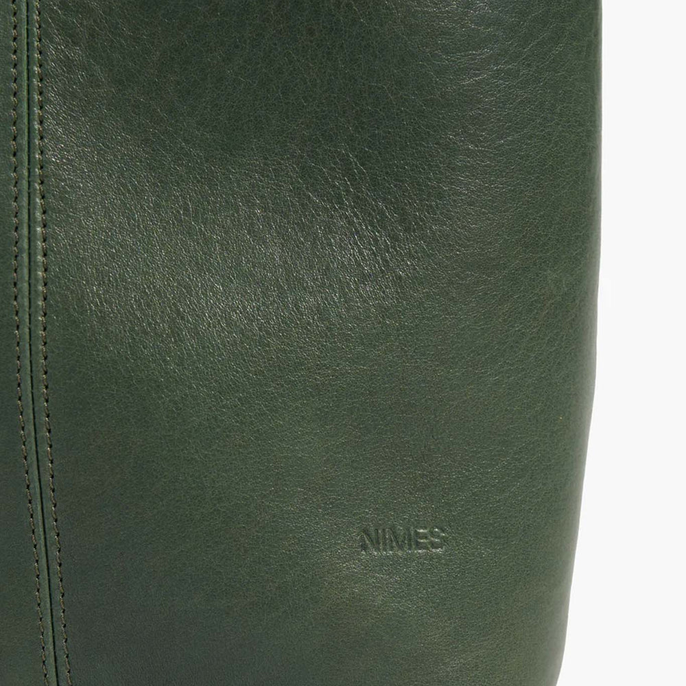 
                  
                    Close-up of a green leather bag with 'Nimes' branding.
                  
                