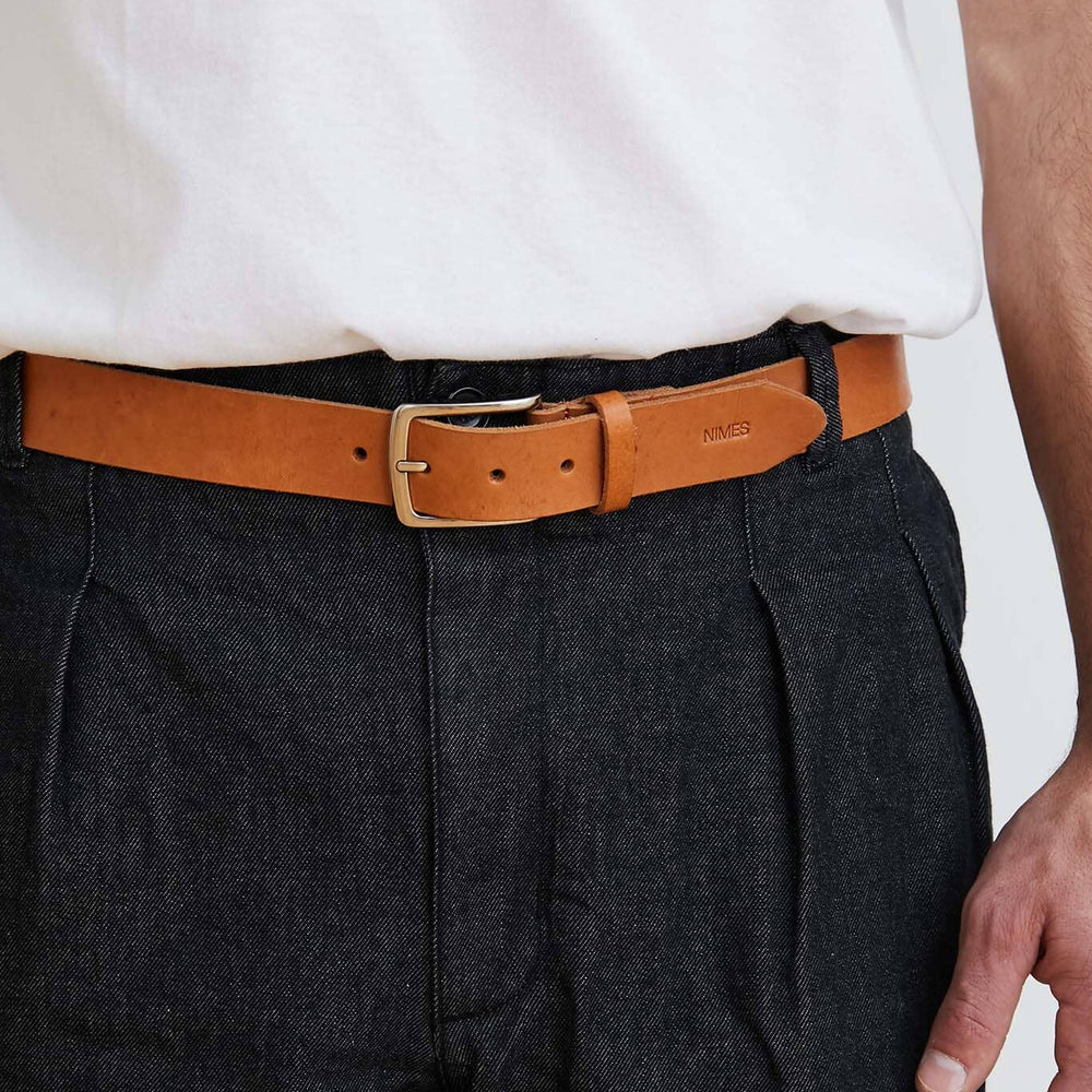 
                  
                    Person wearing a white shirt, dark pants, and a brown belt with a visible brand logo.
                  
                