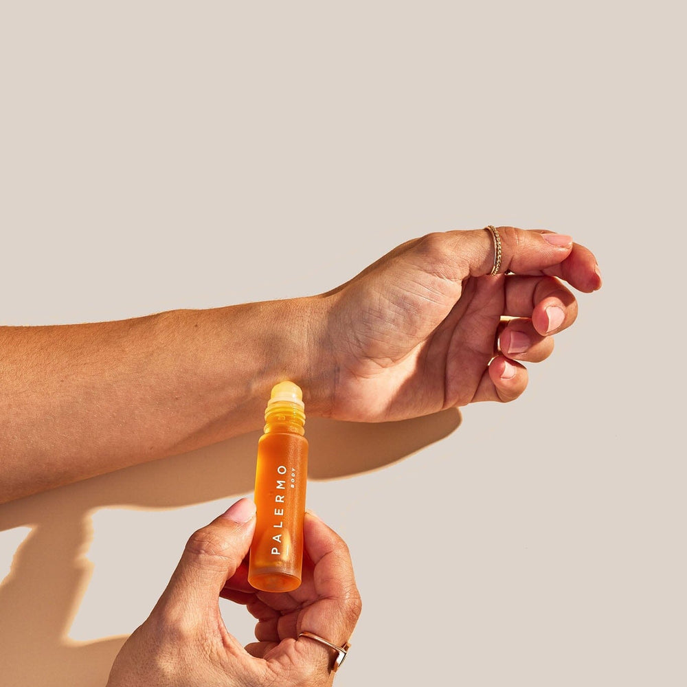 Two hands holding a perfume bottle labeled 'Palermo' against a beige background