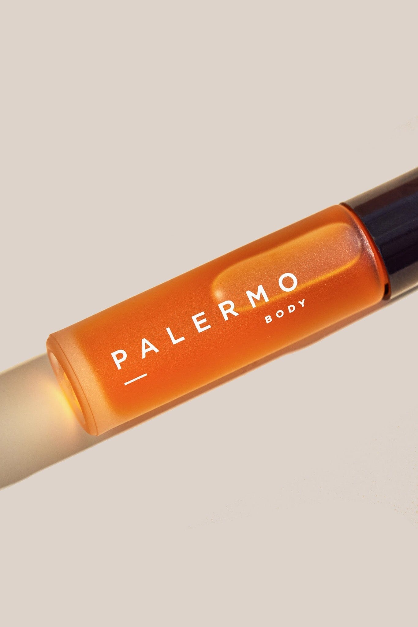 Orange rollerball with 'Palermo Body' branding on a beige background