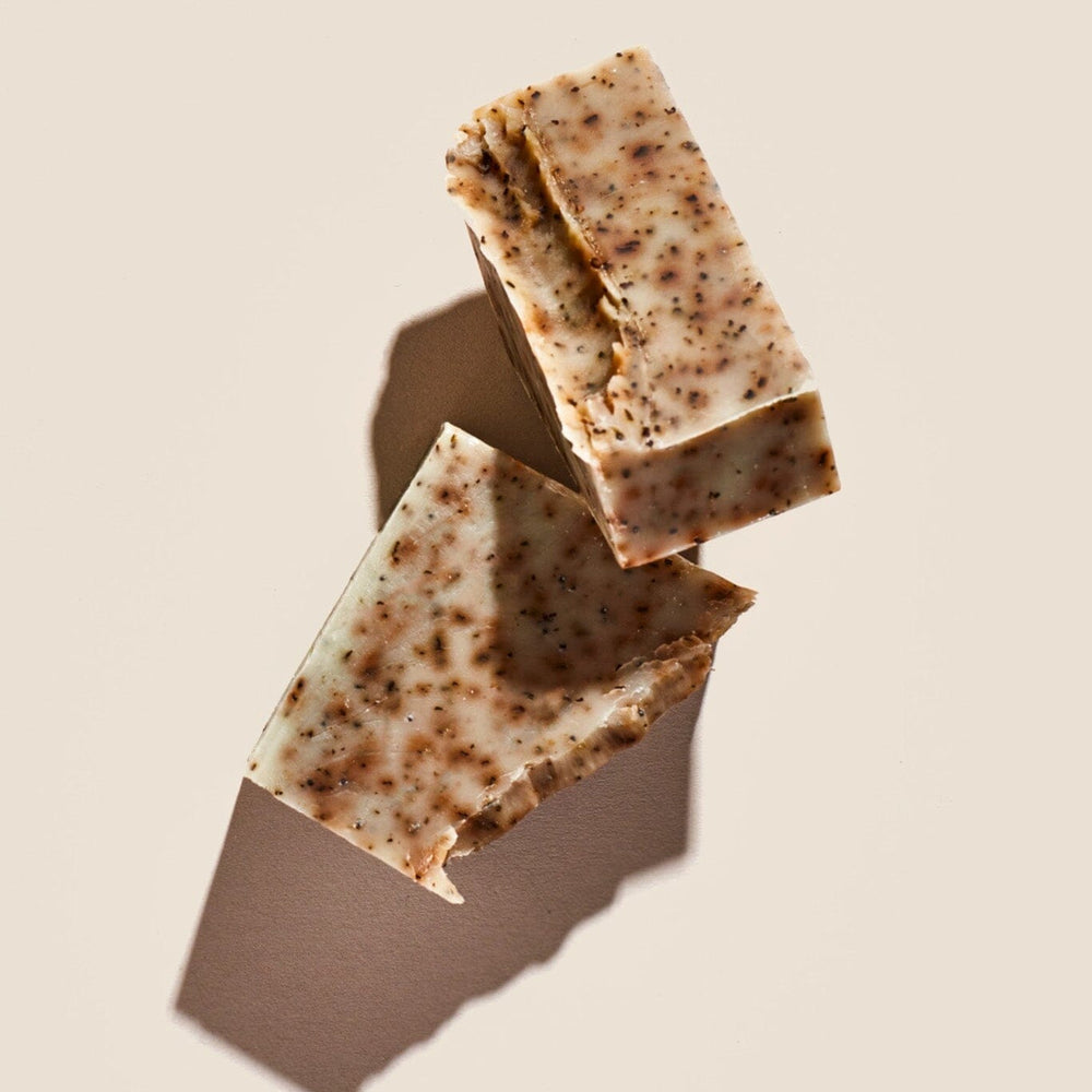 Two bars of soap with a speckled green and brown appearance, placed on a neutral background.