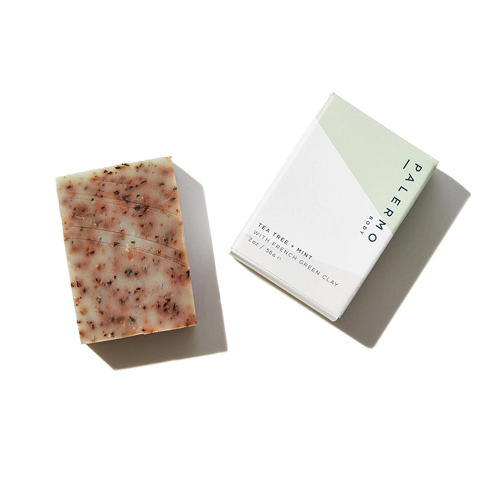 A bar of soap with a textured surface next to its packaging, which is a simple white card with 'Palermo Body' written on it.