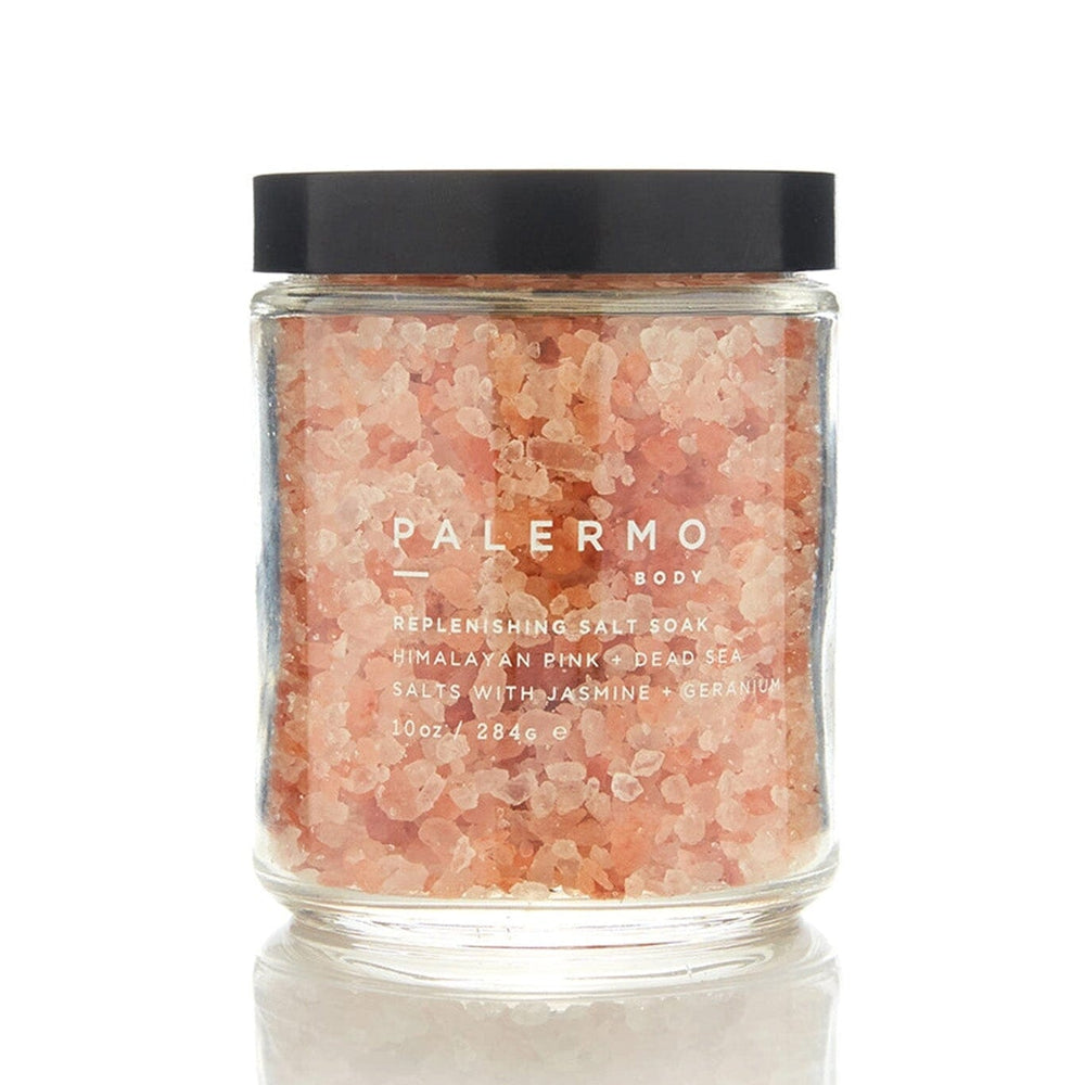 A clear glass jar filled with pink Himalayan salt, with a black lid and a label that reads 'PALERMO BODY HIMALAYAN PINK SALT SOAK'.