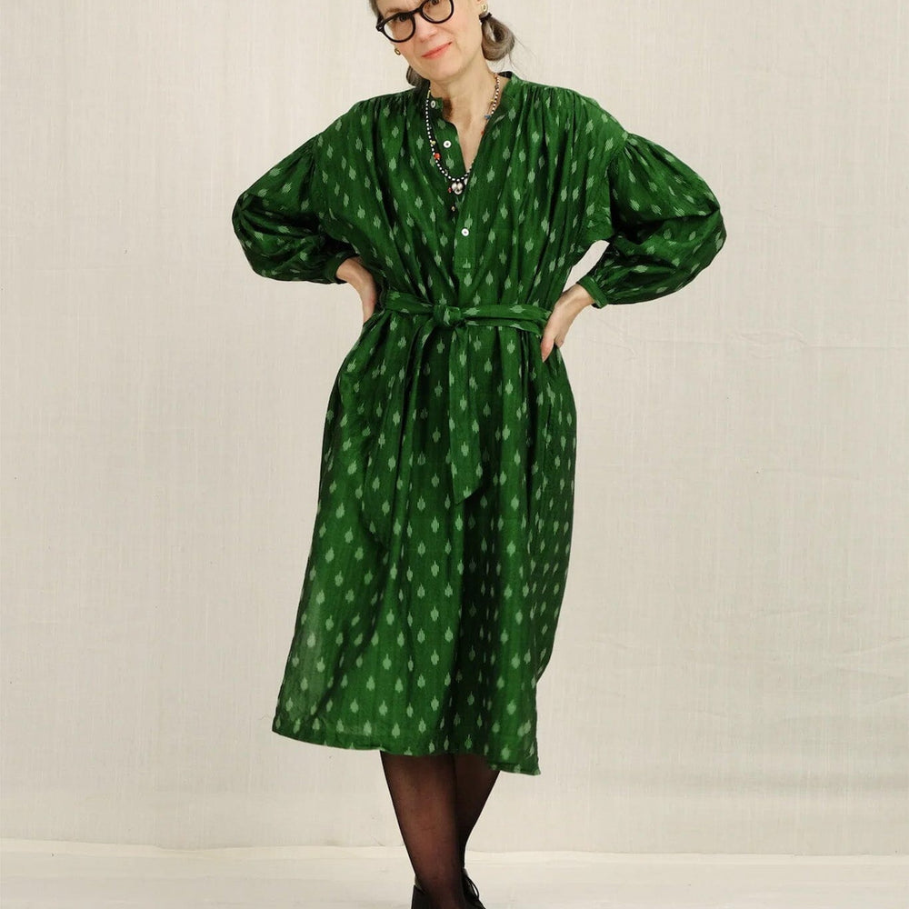 Person wearing a green patterned long sleeve on a plain background