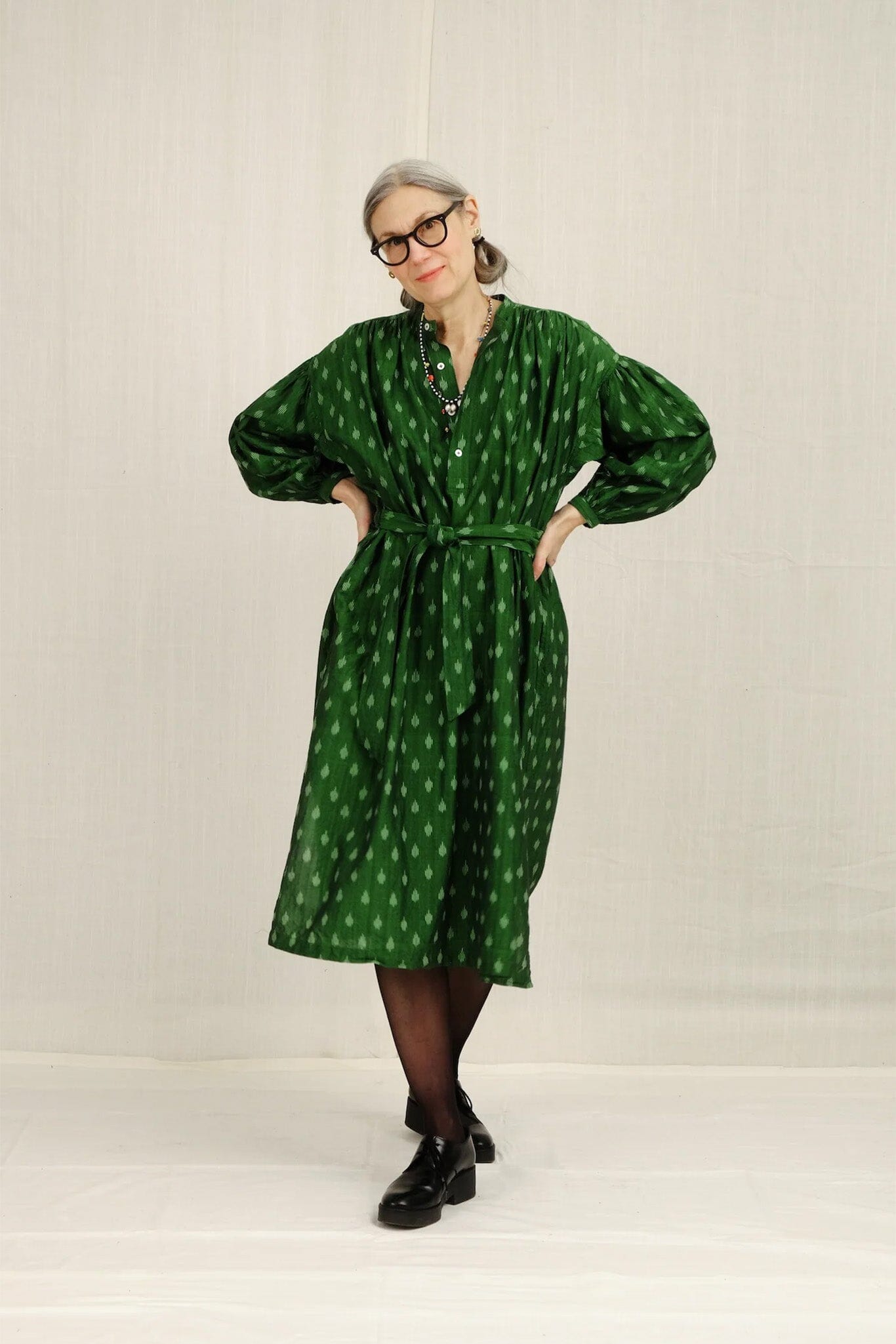 Person wearing a green patterned long sleeve on a plain background