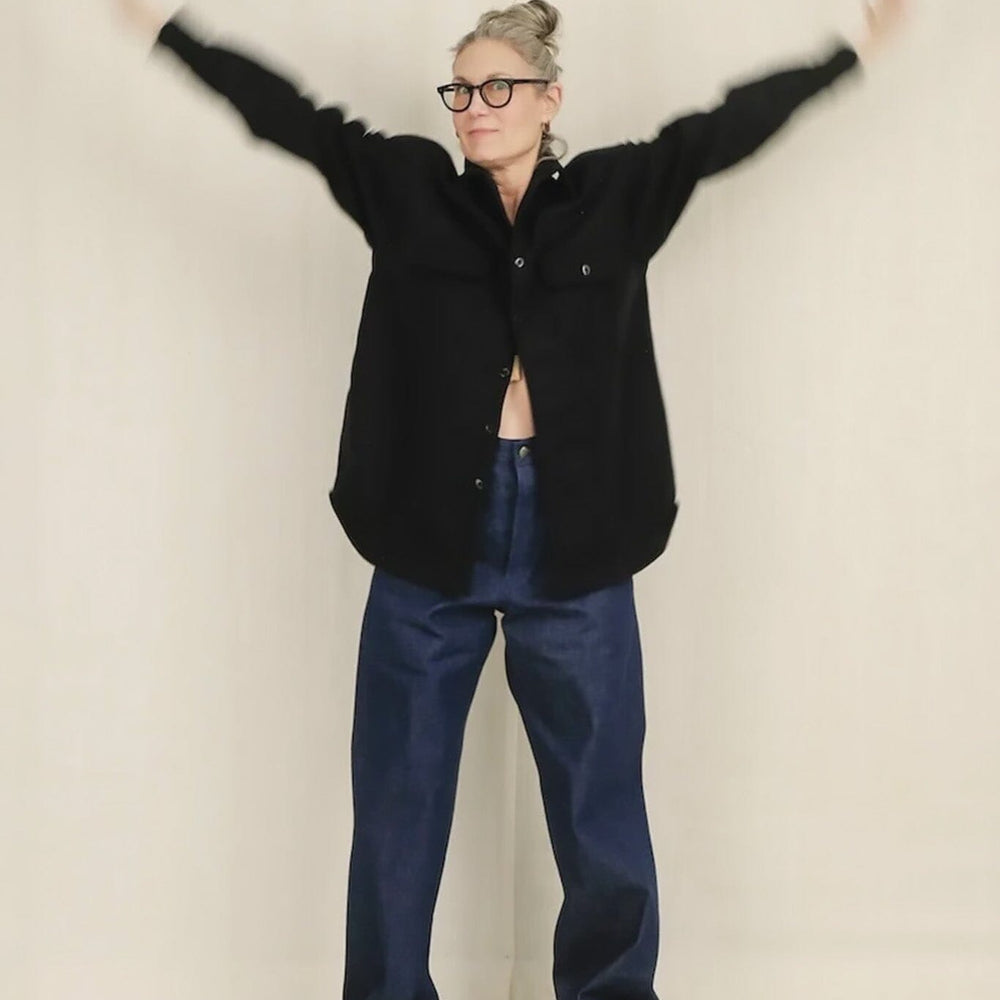 Person wearing a blue jacket and blue pants with arms outstretched on a plain background