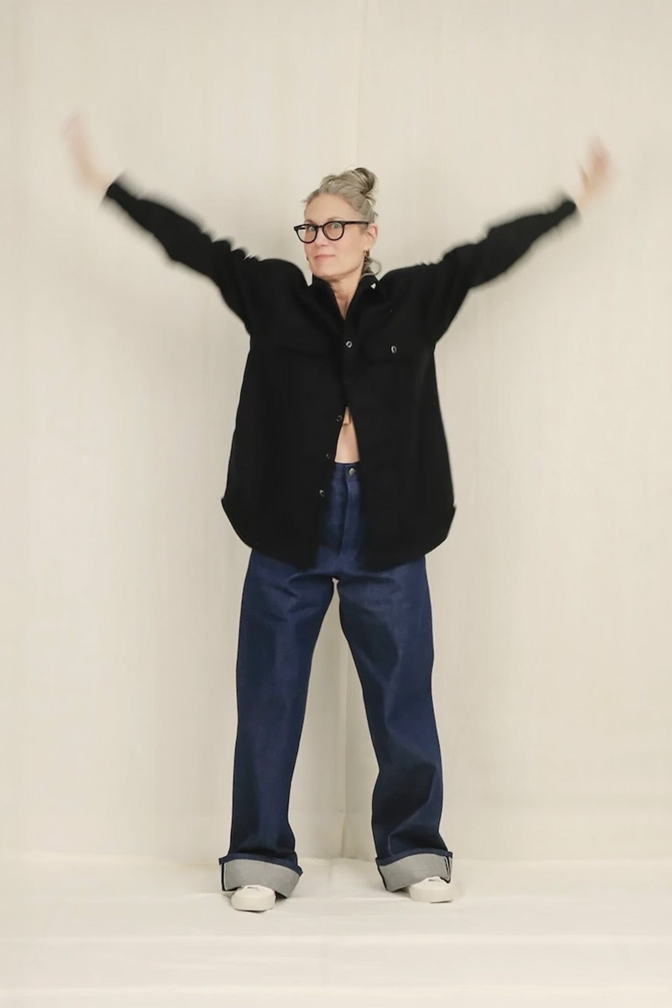 Person wearing a blue jacket and blue pants with arms outstretched on a plain background