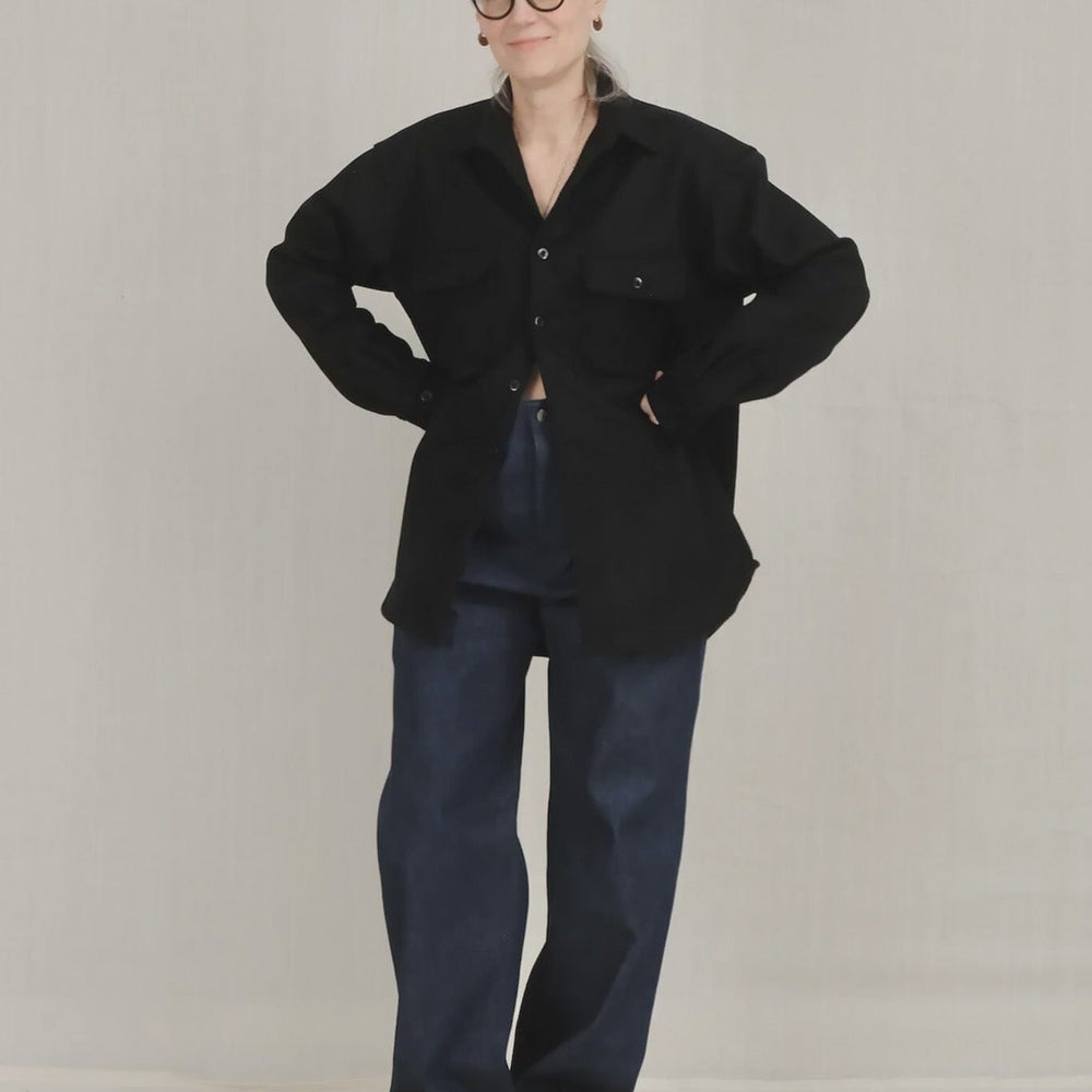 Person wearing a navy top and blue pants on a plain background