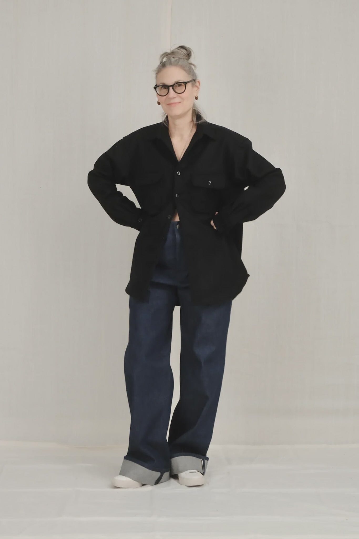 Person wearing a navy top and blue pants on a plain background