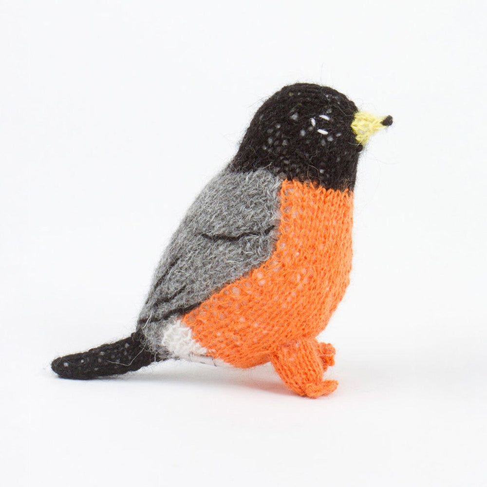 Knitted toy resembling robin with orange, black, and gray colors on a white background
