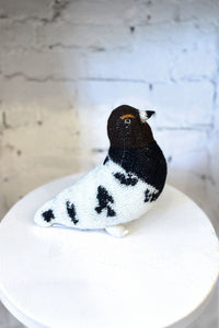 Knitted bird toy on a white surface with a light gray background