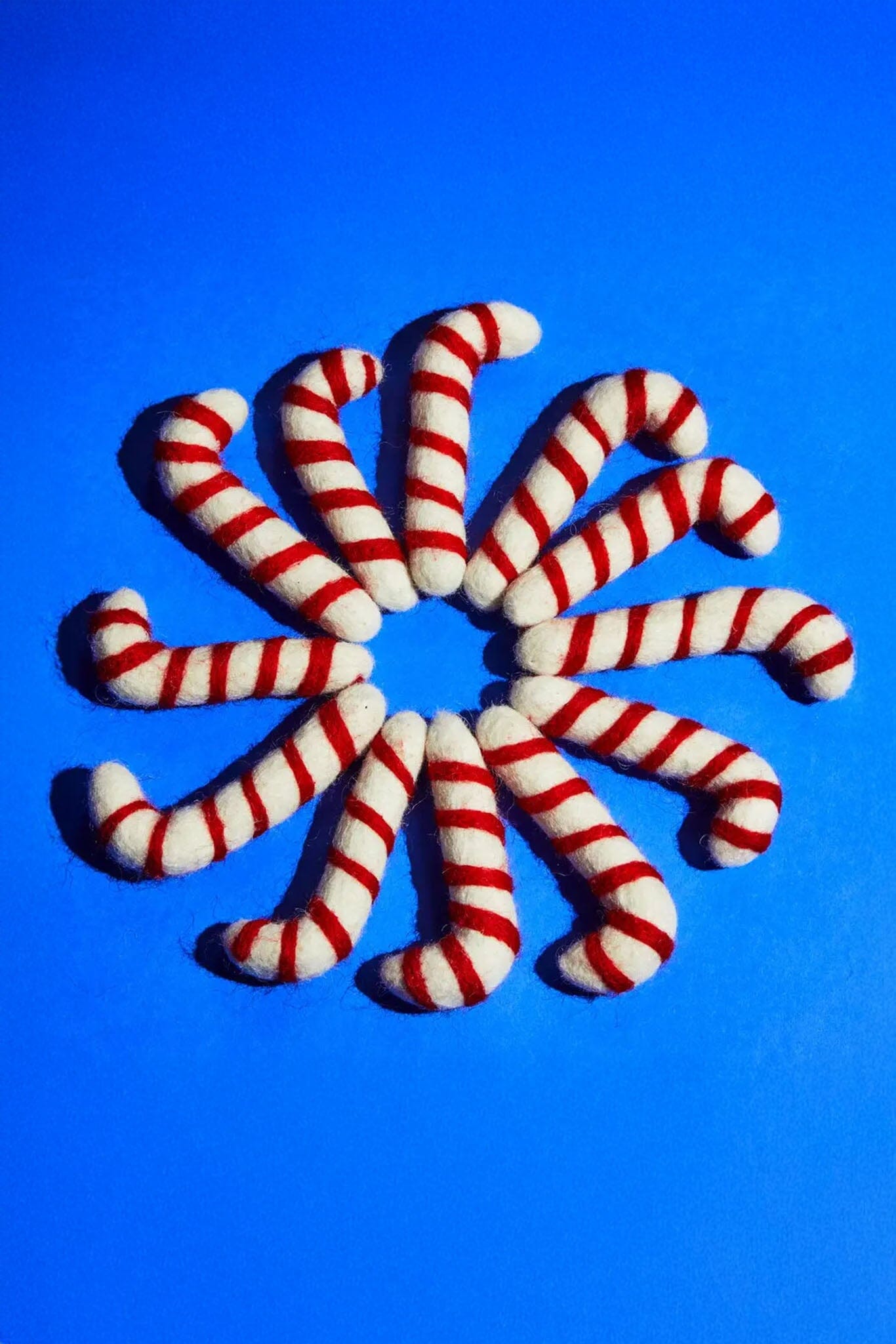 Red and white striped candy cane cat toys arranged in a circular pattern on a blue background