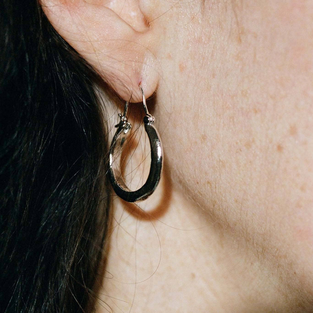 Close-up of a person wearing a silver hoop earring.